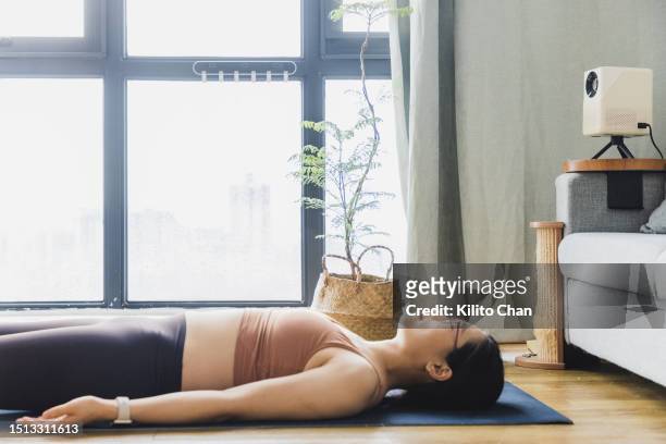 asian woman doing yoga savasana pose at home - savasana stock pictures, royalty-free photos & images