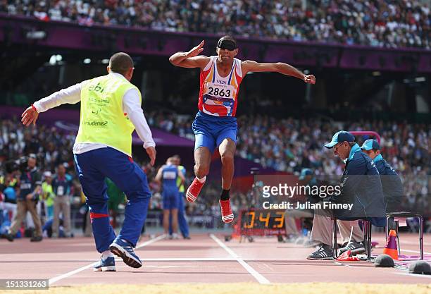 Oscar David Herrera of Venezuela is assisted by his guide as he competes in the Men's Triple Jump - F11 Final on day 8 of the London 2012 Paralympic...