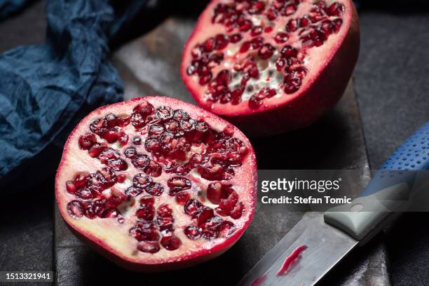 fresh pomegranate slices on a dark wooden cutting board - pomegranate stock pictures, royalty-free photos & images
