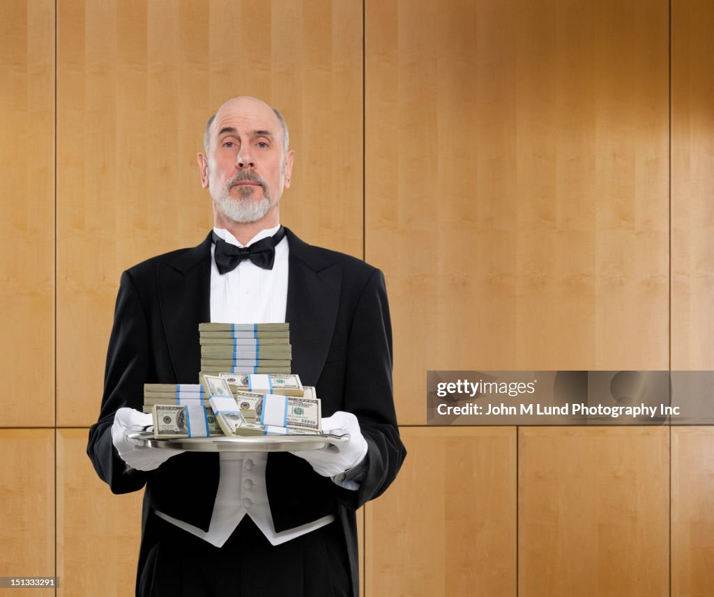 Butler holding tray of cash