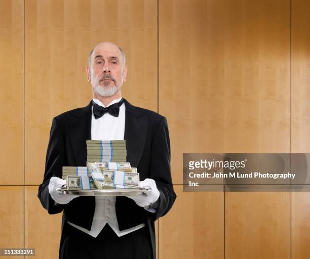 butler holding tray of cash - millionnaire stock pictures, royalty-free photos & images