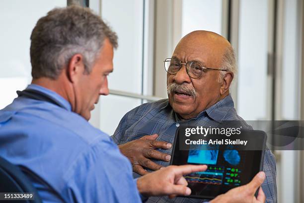 doctor talking to patient in hospital using digital tablet - cardiologist stock pictures, royalty-free photos & images