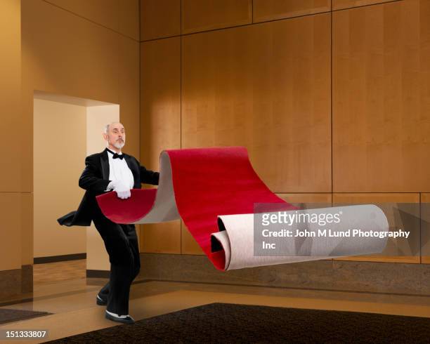 butler unrolling red carpet - red carpet event stock pictures, royalty-free photos & images