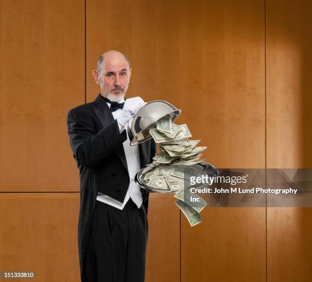 butler dropping cash from covered dish - butler stock pictures, royalty-free photos & images