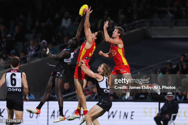 Aliir Aliir of the Power flies with Ben King and Jack Lukosius of the Suns during the 2023 AFL Round 17 match between the Port Adelaide Power and the...