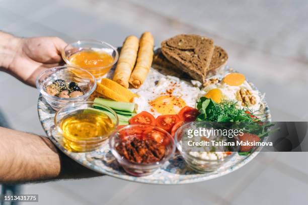 turkish breakfast on a plate in hands close-up. sunny day. - red saucer stock pictures, royalty-free photos & images