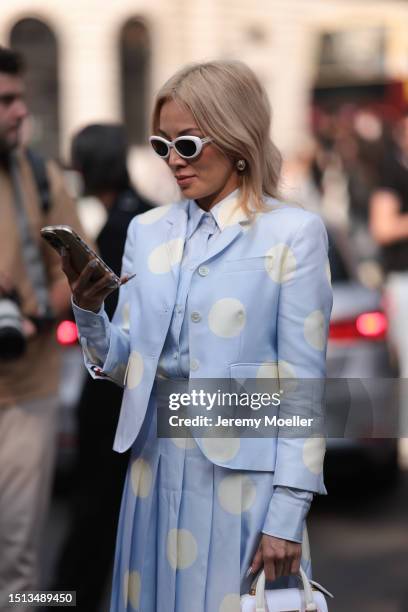 Tina Leung is seen wearing sunglasses in butterfly shape with a big white frame, a matching outfit from Thom Browne in light blue with big white...