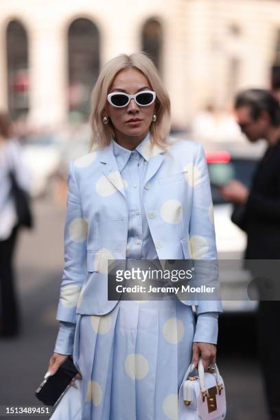 Tina Leung is seen wearing sunglasses in butterfly shape with a big white frame, a matching outfit from Thom Browne in light blue with big white...