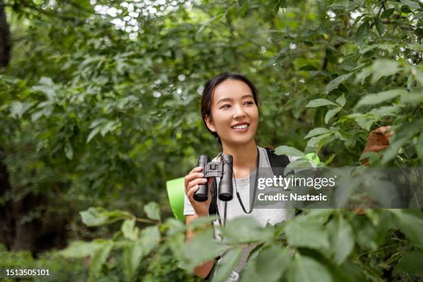 junge asiatische frau im wald, die durch ein fernglas schaut - binoculars woods stock-fotos und bilder