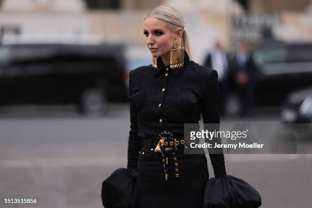 Leonie Hanne seen outside Schiaparelli show wearing big golden Schiaparelli earrings, black ruffled Schiaparelli dress with golden buttons and a big...
