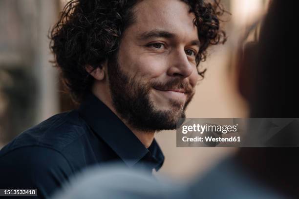 smiling man talking to a friend - kleine scherptediepte stockfoto's en -beelden