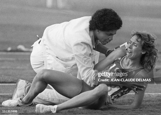 Mary Decker of the USA, comforted by a track official, cries out in frustration after falling down during the women's 3000m final at the Olympic...