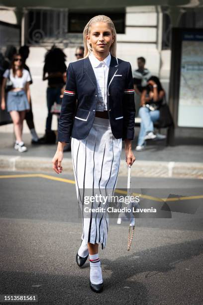 Caroline Daur wears a blue blazer with striped details on the sleeves, white polo top, white and black striped midi skirt, white socks, black heels...