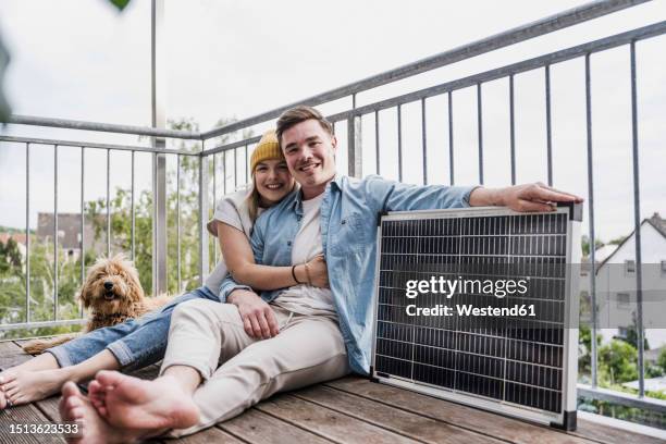 happy couple sitting with solar panel and dog - balcony stock pictures, royalty-free photos & images