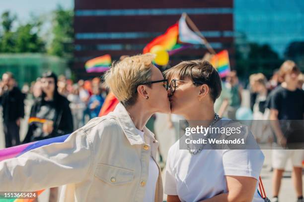 lesbian couple kissing each other at gay pride event on sunny day - photos of lesbians kissing stock pictures, royalty-free photos & images