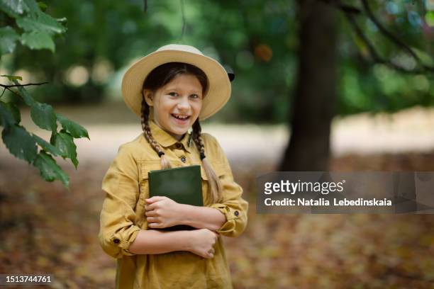 vintage reading journey: captivating portrait of a preteen girl, wearing a wicker hat and pigtails, lost in a book, embracing retro style amid the enchanting ambience of an autumn park or forest. copy space - yellow hat stock pictures, royalty-free photos & images