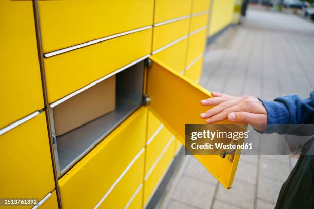 hand of boy opening parcel locker - taquilla recipiente fotografías e imágenes de stock