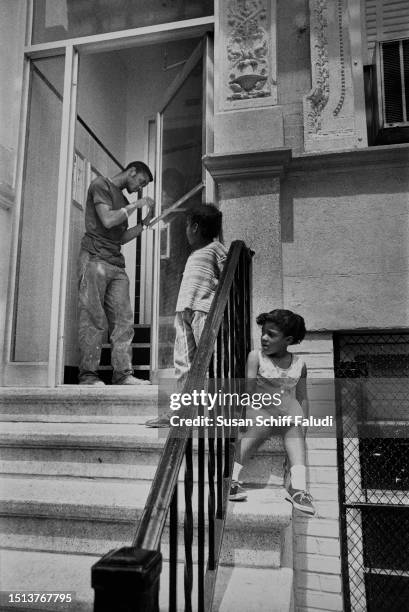 Child Stooping Children sit and stand on the stoop of a property as a labourer, a ...