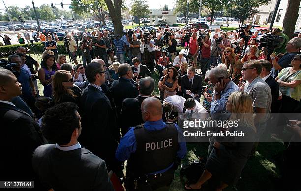Spectators gather as members of disgraced cop Drew Peterson's defense team speak during a news conference outside the Will County Courthouse...