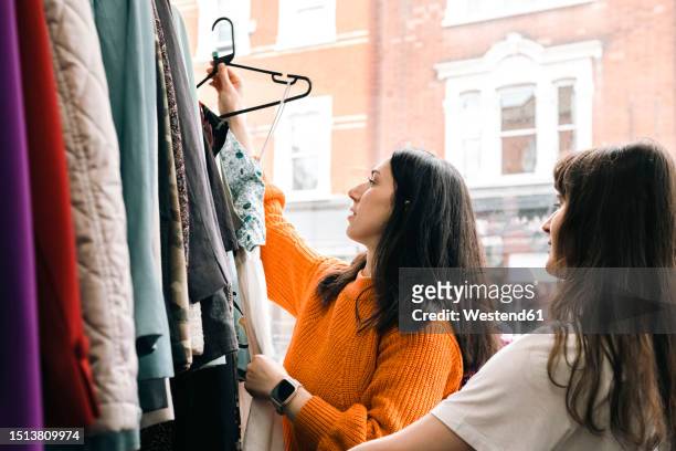 young friends examining clothes in clothing store - second hand stock pictures, royalty-free photos & images