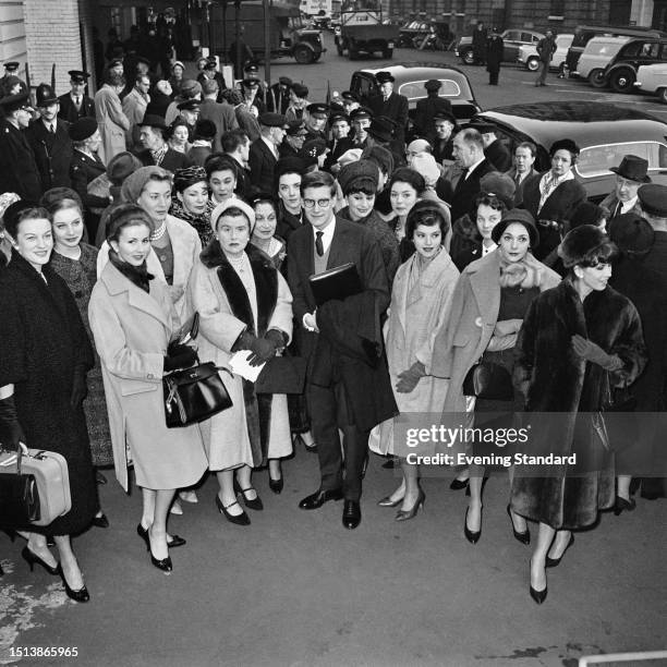 French fashion designer Yves St Laurent poses with a group of fashion models after arriving at Victoria Station in London, November 11th, 1958. St...