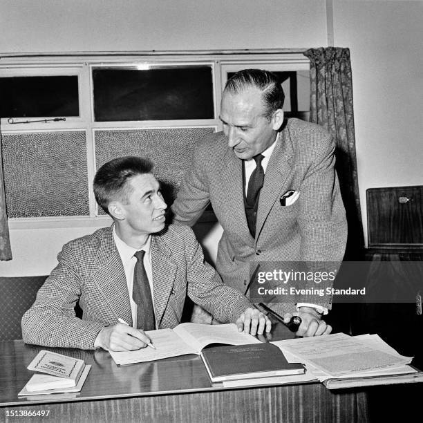 West Ham manager Ted Fenton watches as English footballer Phil Woosnam signs for his club for a fee of £30 November 13th 1958.