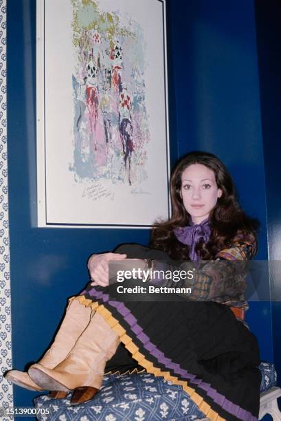 American actress and model Marisa Berenson sitting next to a painting by artist LeRoy Neiman, New York, December 11th 1975.