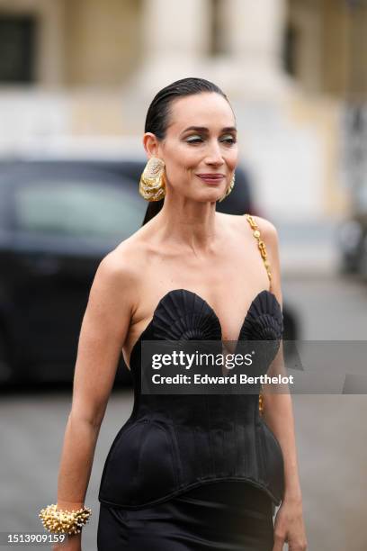 Guest wears a gold and diamonds oversized earring from Schiaparelli, a black V-neck / shoulder-off embossed chest corset from Schiaparelli, a black...