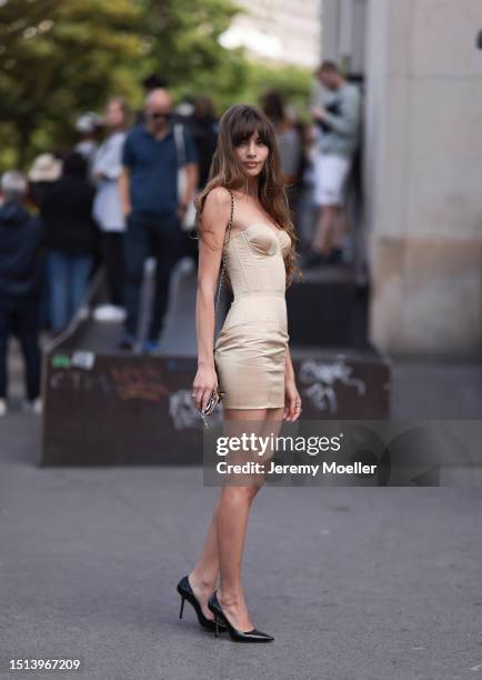 Fashion Week guest is seen wearing a strapless formfitting golden corset mini dress, a small black leather hardback from Chanel and black pointed...