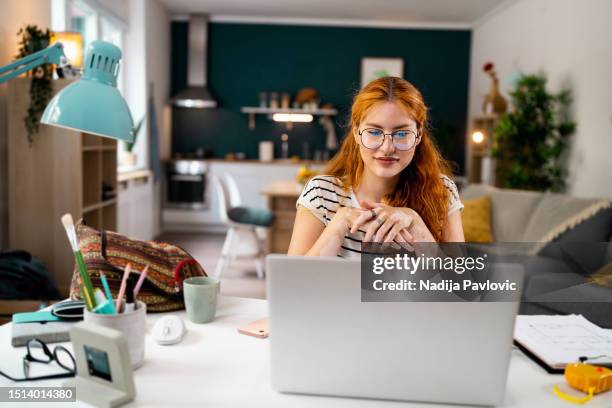 redhead female freelancer with vitiligo and acne on her face, having a video call while working from home - pleased face laptop stock pictures, royalty-free photos & images