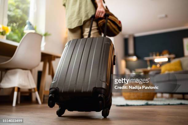 donna irriconoscibile che tira la valigia nell'appartamento - bagagli foto e immagini stock