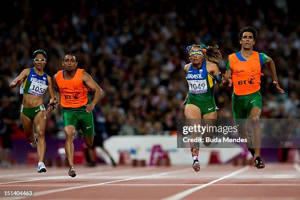 Terezinha Guilhermina of Brazil and guide Guilherme Soares de Santana cross the line to win gold ahead of silver medallists Jerusa Gerber Santos of...