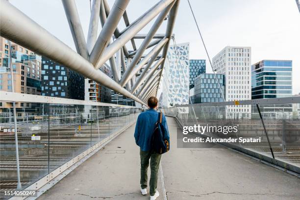 rear view of a man on the akrobaten (the acrobat) pedestrian bridge, oslo, norway - oslo business stock pictures, royalty-free photos & images