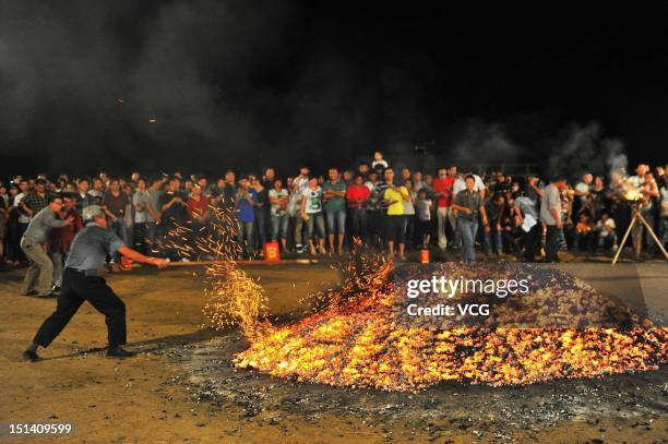 People prepare burning embers during a traditional Firewalking ceremony in hope of avoiding disasters on September 6, 2012 in Pan an County, Zhejiang...