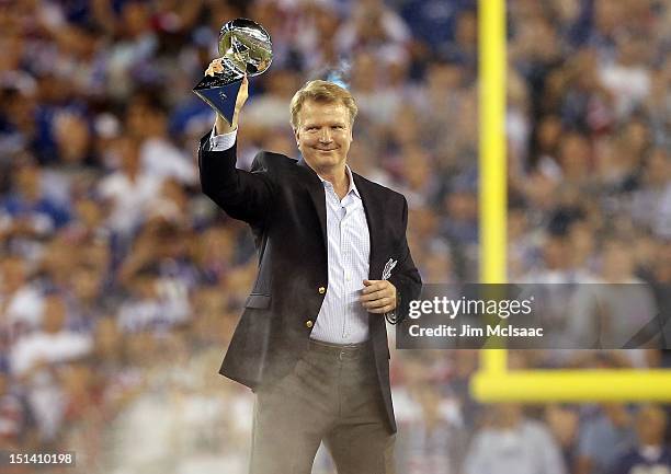 Former New York Giant Phil Simms holds the Vince Lombardi trophy during pre game ceremonies before the Giants play against the Dallas Cowboys at...