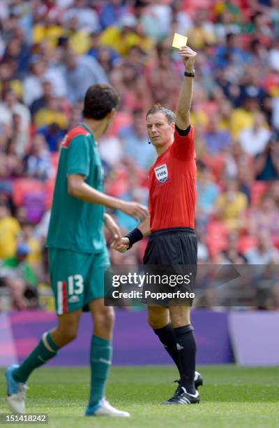 Referee Mark Clattenburg of Great Britain shows a yellow card to Diego Reyes of Mexico during the Men's Football Final between Brazil and Mexico on...