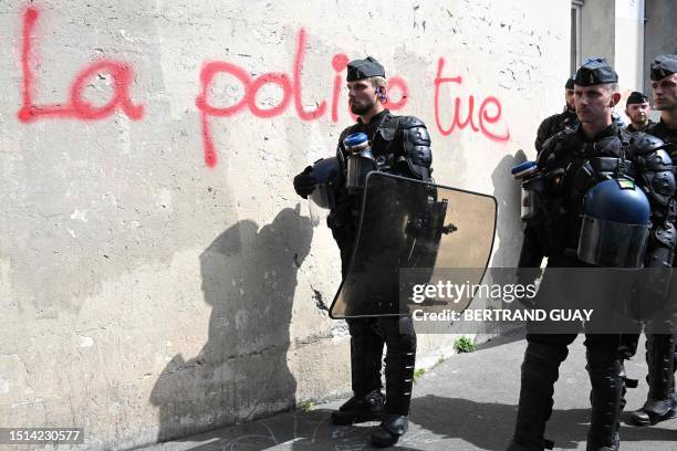 Riot mobile gendarmes stand guard next a graffiti reading "police kills" during the "March for Adama Traore" - seven years after his death - at Gare...
