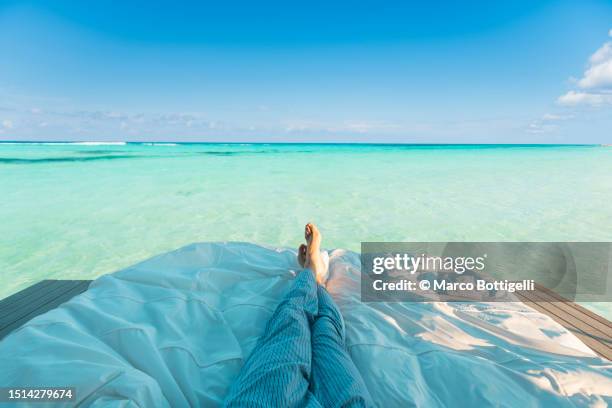 personal perspective of person relaxing on a bed on an overwater bungalow in the caribbean sea - lyric stock pictures, royalty-free photos & images