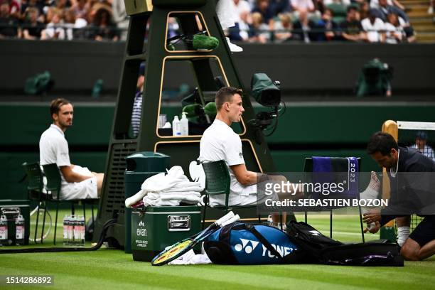 Hungary's Marton Fucsovics has his foot checked by a doctor during his men's singles tennis match against Russia's Daniil Medvedev on the sixth day...