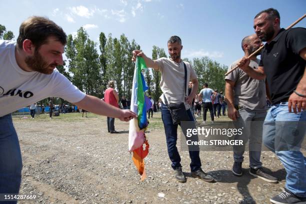 Anti-LGBTQIA+ activists burn a rainbow flag as they try to disrupt Tbilisi Pride Festival in Tbilisi on July 8, 2023.