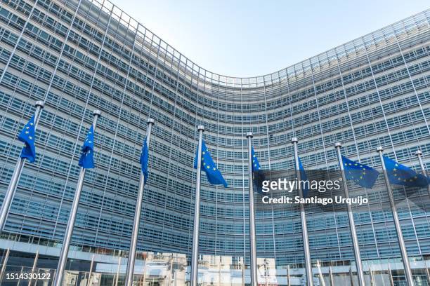 european union flags waiving in front of berlaymont building of the european commission - quartier européen bruxelles photos et images de collection