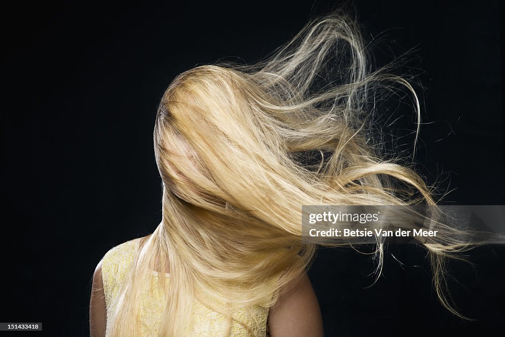 Woman covered with blowing hair in wind.