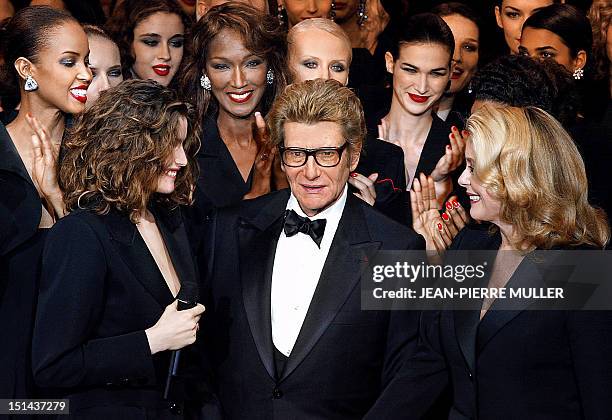 French designer Yves Saint-Laurent salutes the crowd with French model Laetitia Casta and French actress Catherine Deneuve at the Centre Georges...