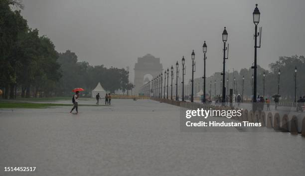 People walking through a water logged Central Vista Lawns after the Heavy rainfall at India Gate on July 8, 2023 in New Delhi, India. Delhi-NCR was...