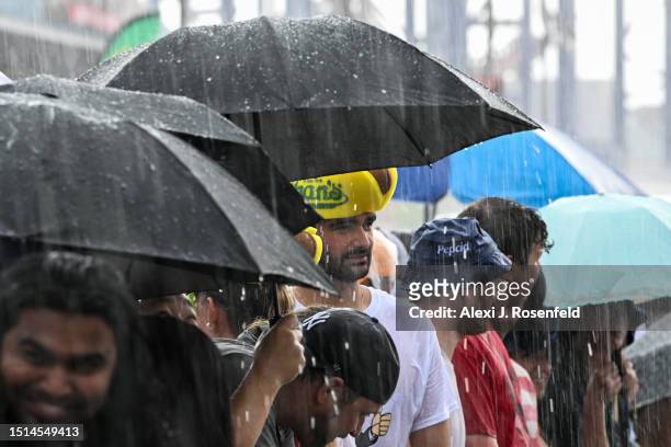 Spectators take cover as a thunderstorm hits before the men's competition during the 2023 Nathan's Famous Fourth of July International Hot Dog Eating...