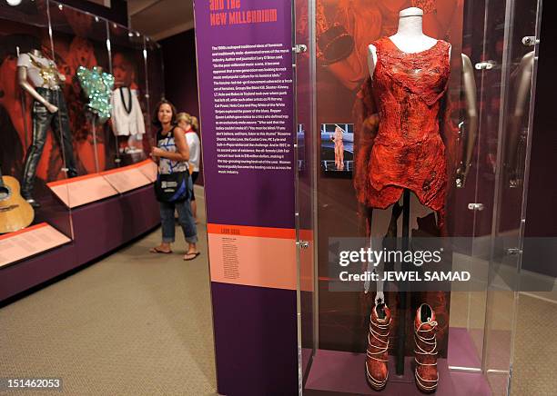 Visitors look at the raw meat dress worn by Lady Gaga at a 2010 awards ceremony during "Women Who Rock; Vision, Passion, Power" exhibition at the...