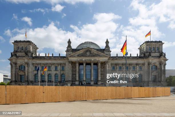 deutscher bundestag behind a construction site fence - reichstag building with german flags (german parliament building) - berlin, germany - central berlin stock-fotos und bilder