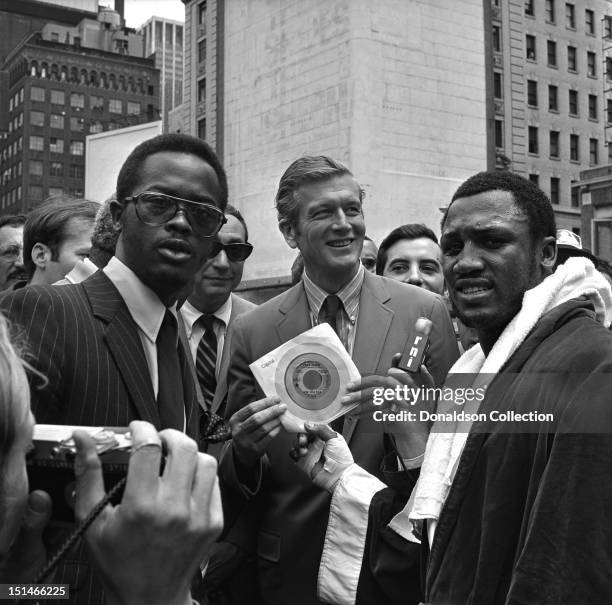 Heavyweight contender Joe Frazier hands his latest single 'If You go, Stay Gone' to Mayor John Lindsey while Locke Edwards and Howard Cosell look on,...