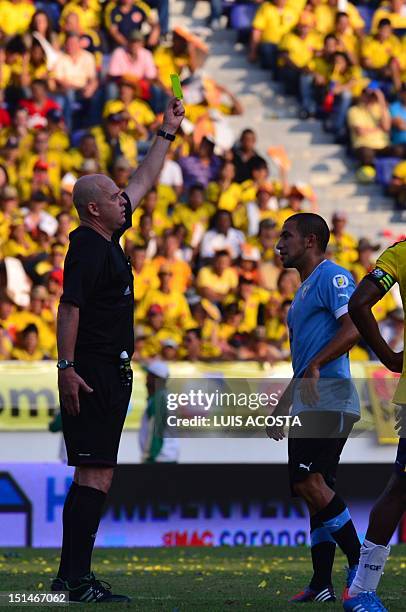 Brazilian referee Heber Lopes shows the yellow card to Uruguay's Walter Gargano during the Brazil 2014 World Cup South American qualifier football...