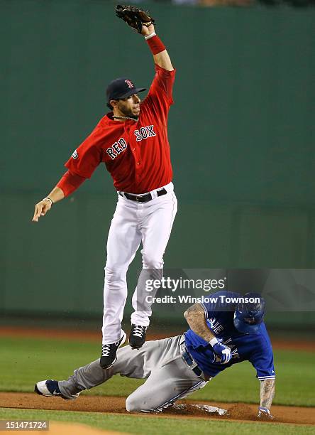 Mike Aviles of the Boston Red Sox goes high to get a throw as Brett Lawrie of the Toronto Blue Jays slides in safely with a double during the first...